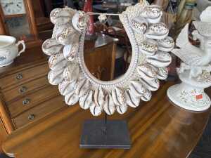 Handmade decorative spotted cowrie shell necklace on a stand