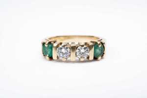 An emerald and diamond ring in 14 carat yellow gold