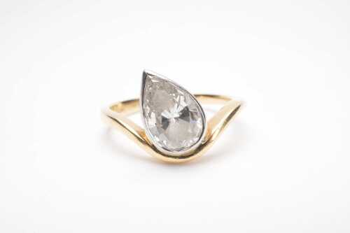 A bezel set pear cut diamond solitaire ring in 18ct yellow and white gold