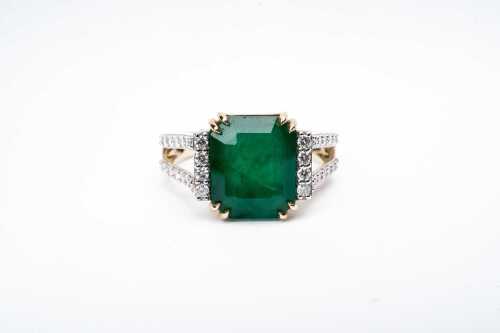 An emerald and diamond ring in 14 carat yellow gold