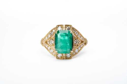 An emerald and diamond ring in 14 carat yellow gold