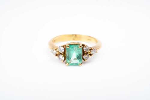 An emerald and diamond ring in 18 carat yellow gold