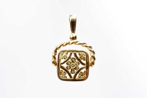 A carved spinner pendant in 9 carat yellow gold