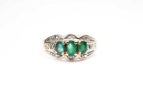 An emerald and diamond ring in 9 carat yellow gold