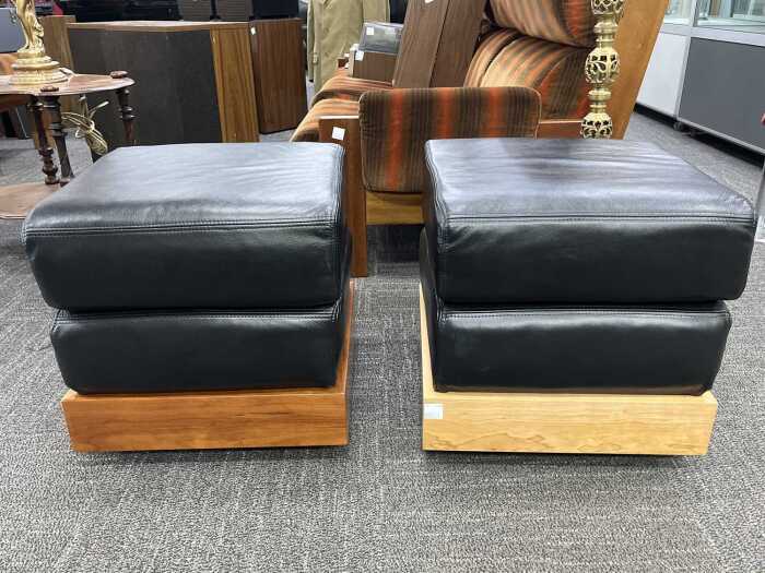 Pair of leather ottomans with timber plinth bases