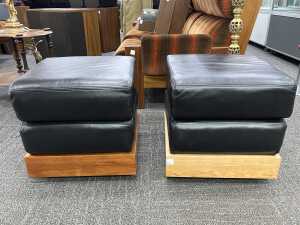 Pair of leather ottomans with timber plinth bases