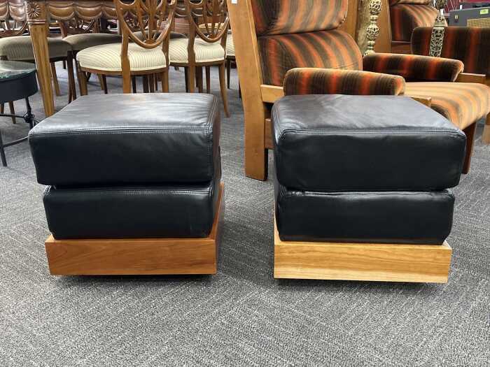 Pair of leather ottomans with timber plinth bases