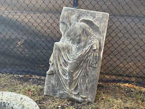 A reproduction stone plaque of 'Nike Fixing Her Sandal'