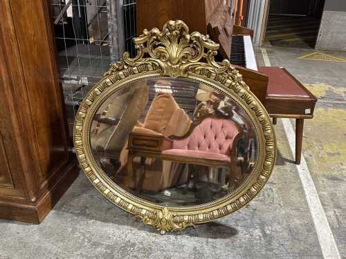 Oval-shaped ornate gilt-framed mirror