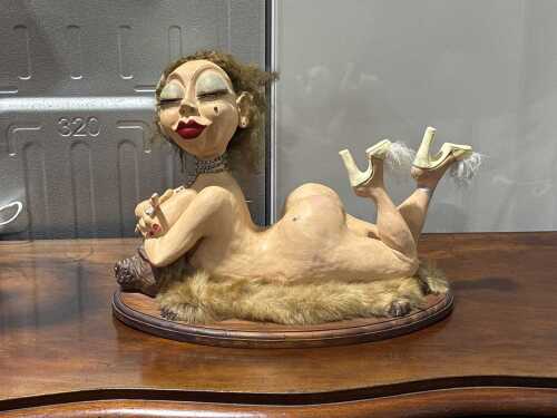 Vintage-style art sculpture featuring a stylised female figure reclining on a fur