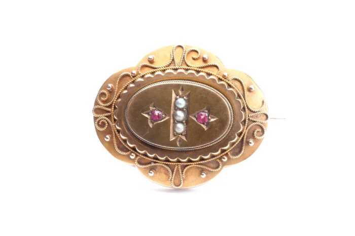 An antique seed pearl and garnet mourning brooch in 15 carat yellow gold
