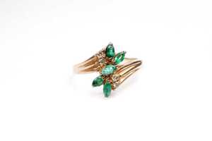 An emerald and diamond ring in 9 carat yellow gold
