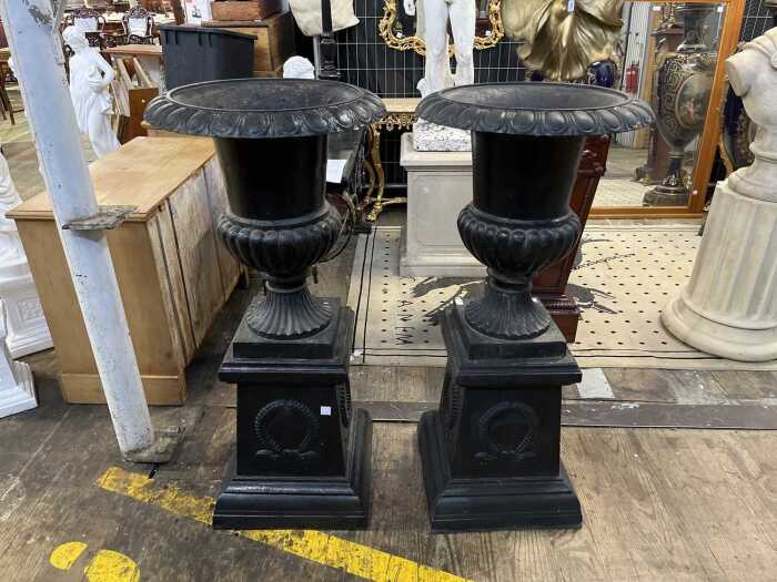 Pair of cast iron urns on pedestals