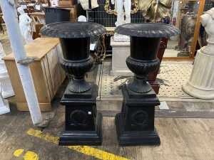 Pair of cast iron urns on pedestals