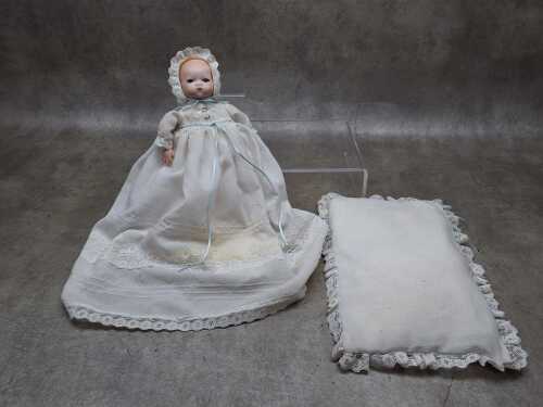Vintage bisque porcelain doll adorned with a white christening gown and bonnet