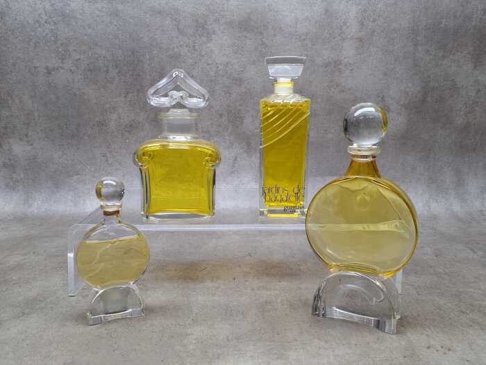 Four perfume display bottles including Guerlain Paris.