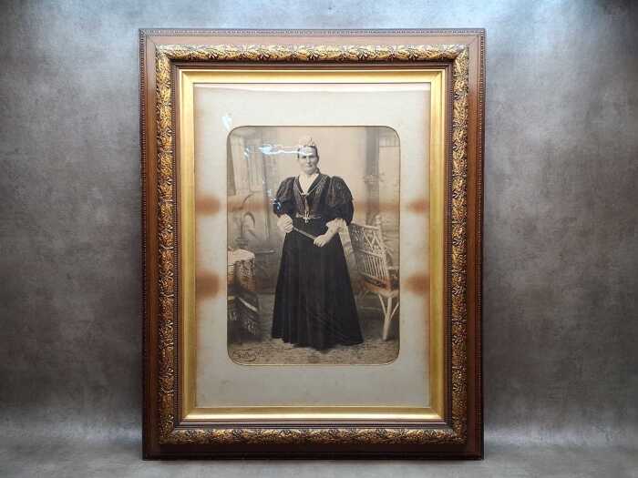 Antique photographic studio portrait of a standing woman