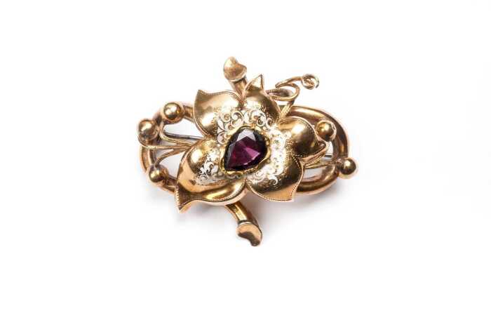 An antique floral garnet and enamel brooch in 15 carat yellow gold