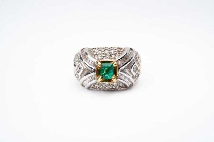 An emerald and diamond ring in 18 carat yellow gold