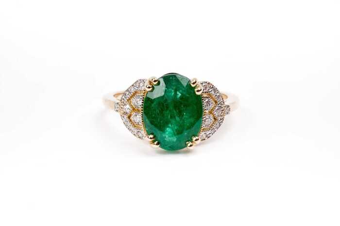 An emerald and diamond ring in 14 carat yellow gold
