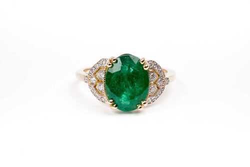 An emerald and diamond ring in 14 carat yellow gold
