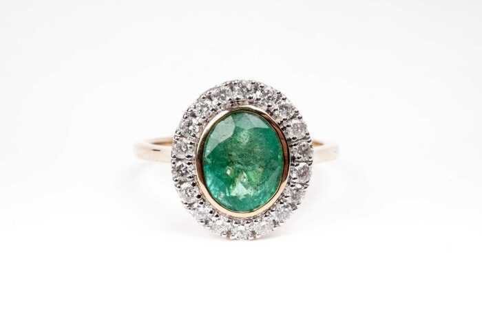 An emerald and diamond ring in 14 carat yellow gold