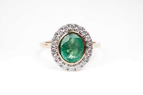 An emerald and diamond ring in 14 carat yellow gold