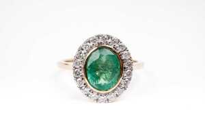 An emerald and diamond ring in 14 carat yellow gold