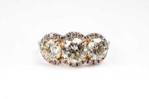 A trilogy halo diamond ring in 14 carat yellow gold