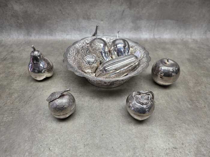 Collection of eight metal beetle nut boxes in a hammered and pieced bowl