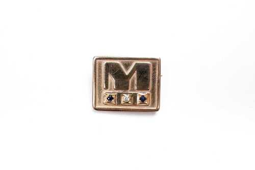A sapphire and diamond M Brooch in 9 carat yellow gold