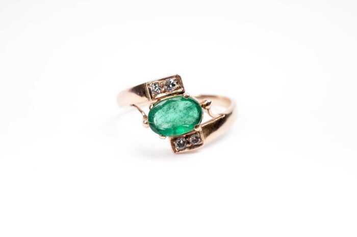 An emerald and diamond ring in 9 carat yellow gold