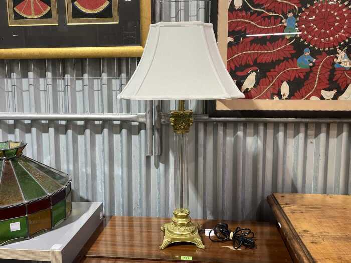 Neo-classical-style table lamp with clear column and gold-tone base.