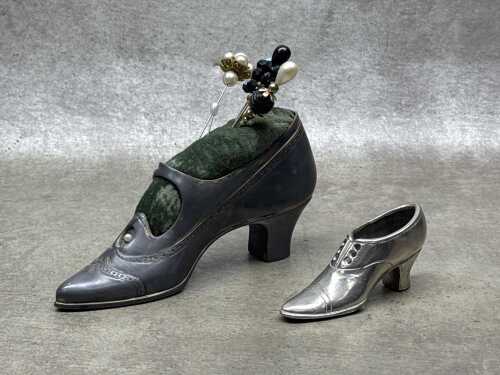 Two cast metal shoes, including a pin cushion with hat pins