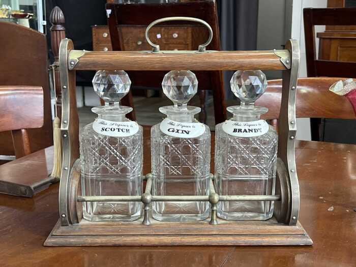 Antique timber tantalus with cut crystal decanters, brass fittings and key