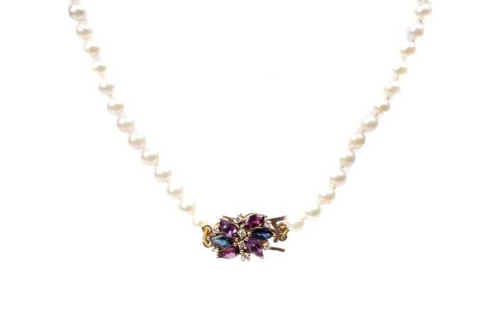 A strand of pearls with an amethyst, sapphire, garnet and diamond clasp in 9 carat yellow gold