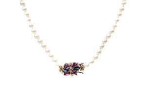 A strand of pearls with an amethyst, sapphire, garnet and diamond clasp in 9 carat yellow gold