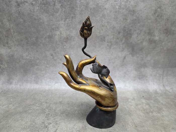 Cast metal sculpture of Buddha hand holding a lotus flower