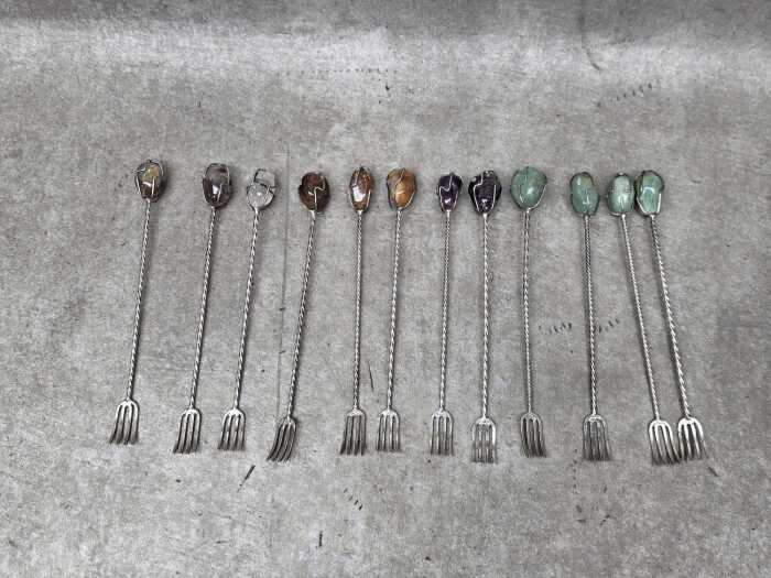 Twelve silver-plated pickle forks mounted with semi-precious stones