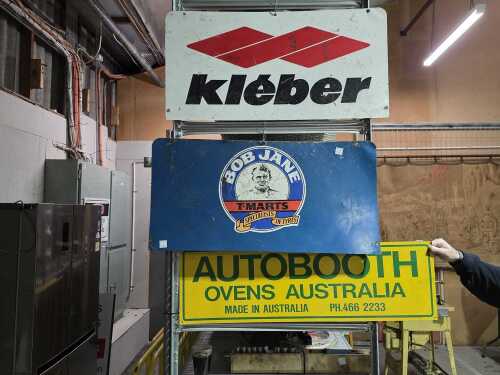 Three metal automotive advertising signs including a double-sided one.