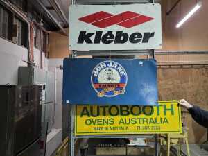 Three metal automotive advertising signs including a double-sided one.