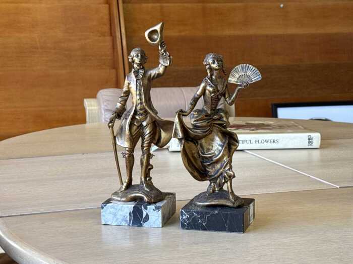 Two decorative gold tone resin figures on a marble base