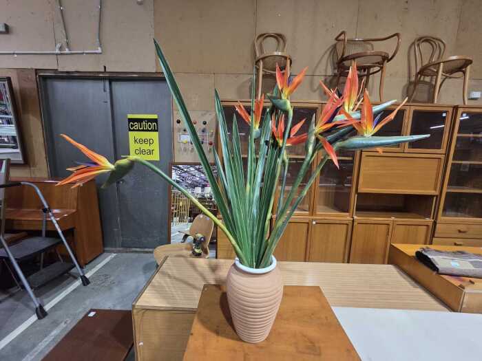Terracotta ribbed vase displaying vibrant artificial Birds of Paradise blooms
