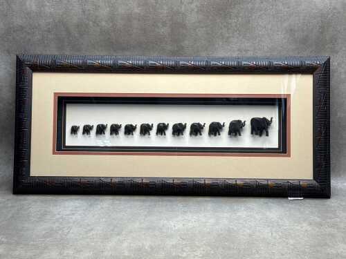 'The Migration, twelve graduated carved timber elephants in shadow box