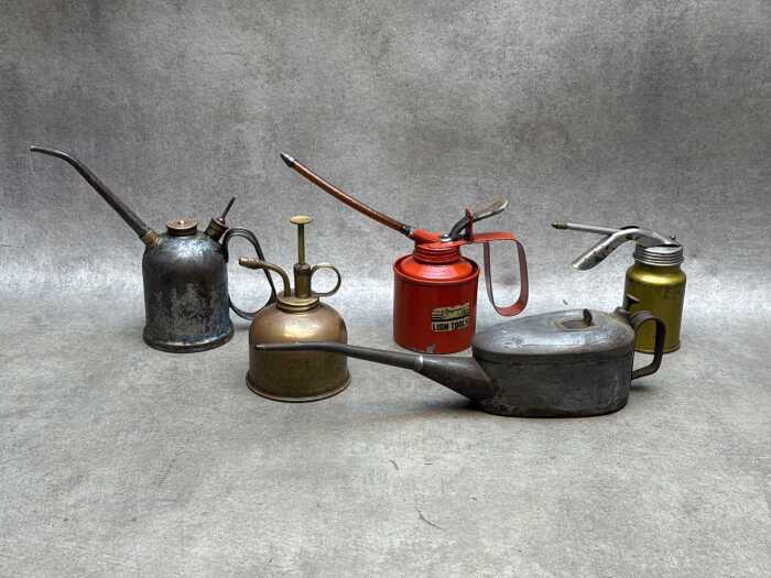 Five garage oil cans, including brass