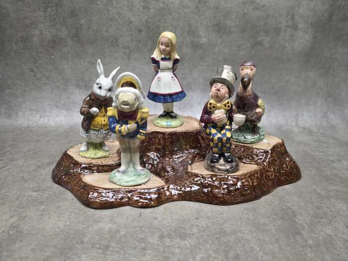 Collection of five Beswick 'Alice in Wonderland' porcelain figures on tree root stand