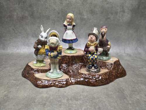 Collection of five Beswick 'Alice in Wonderland' porcelain figures on tree root stand