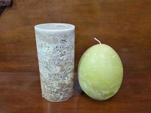 Two textured decorative candles, including pillar and egg shapes.
