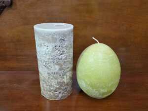 Two textured decorative candles, including pillar and egg shapes.