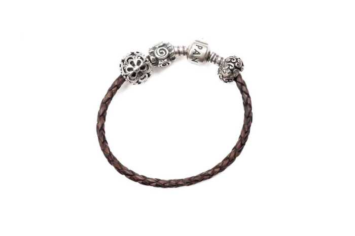 A Pandora brown leather bracelet and three retired charms in sterling silver